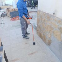 Técnico de Arepal Services localizando una fuga de agua en el suelo de un patio